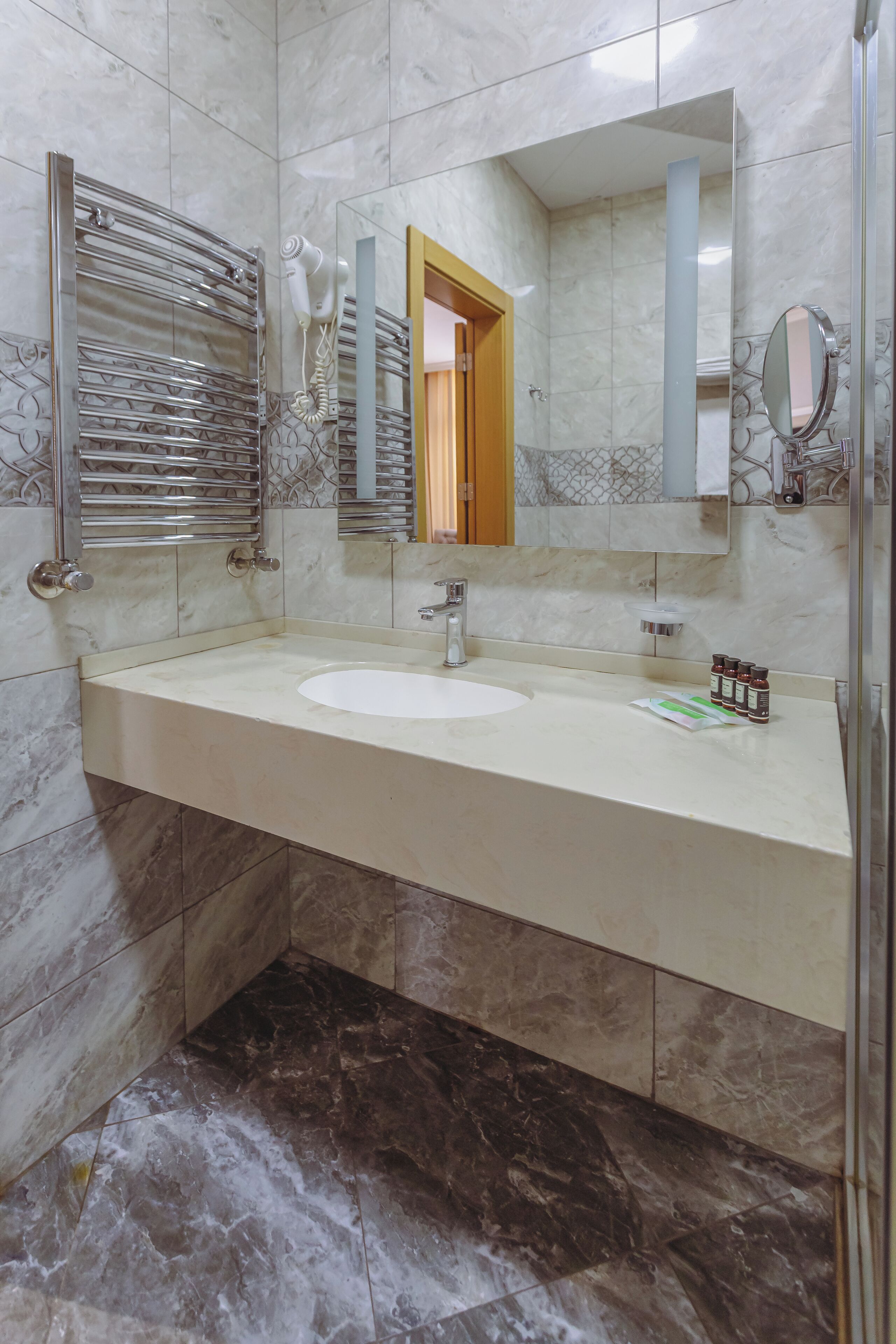 A bathroom with a marble sink, a glass shower enclosure, and a vanity mirror.