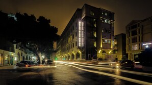 A hotel with a prominent sign, a wet street, and light trails from moving vehicles. - METRO CITY HOTEL (Baku)