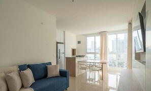 Un appartement moderne avec un canapé bleu, un coin repas et une cuisine.
