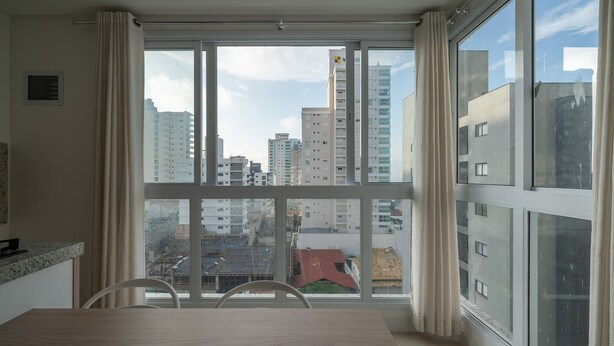 Una habitación moderna con un ventanal grande, una mesa de comedor y vistas a la ciudad.