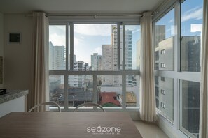 Een moderne kamer met een groot raam, een eettafel en uitzicht op de stad.