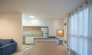 Une cuisine moderne avec des meubles blancs, une table à manger en bois et un canapé bleu.