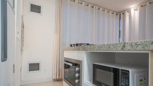 Una cocina compacta con horno empotrado, microondas y cocina a gas.