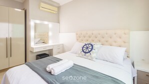 Una camera d'albergo con un letto, una toeletta con specchio, un armadio e un condizionatore d'aria a parete.