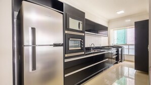 Una cucina moderna con frigorifero in acciaio inossidabile, forno integrato e microonde.