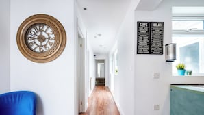 A hallway with a clock, a blue chair, and a menu board listing cafe and gelati options. - 2 Bedroom flat in Putney by the river (London)
