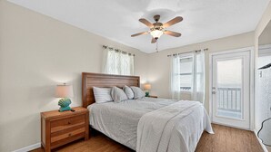 Ein Schlafzimmer mit einem hölzernen Bett, zwei Nachttischen, einem Deckenventilator und Blick durch die Tür.