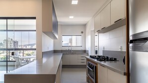 A modern kitchen with a large island, stainless steel appliances, and a view of the city through large windows. - Cozy Apt 550m From the Beach in Porto Belo Lnb502 (Porto Belo)