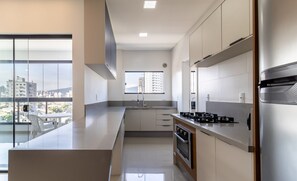 A modern kitchen with a large island, stainless steel appliances, and a view of the city through large windows. - Cozy Apt 550m From the Beach in Porto Belo Lnb502 (Porto Belo)