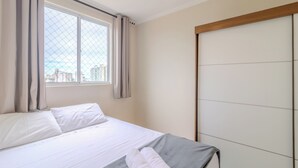 A hotel room with a bed, a window with curtains, and a view of buildings. - Building With a Pool 400m From Beach - LEA (Picarras)