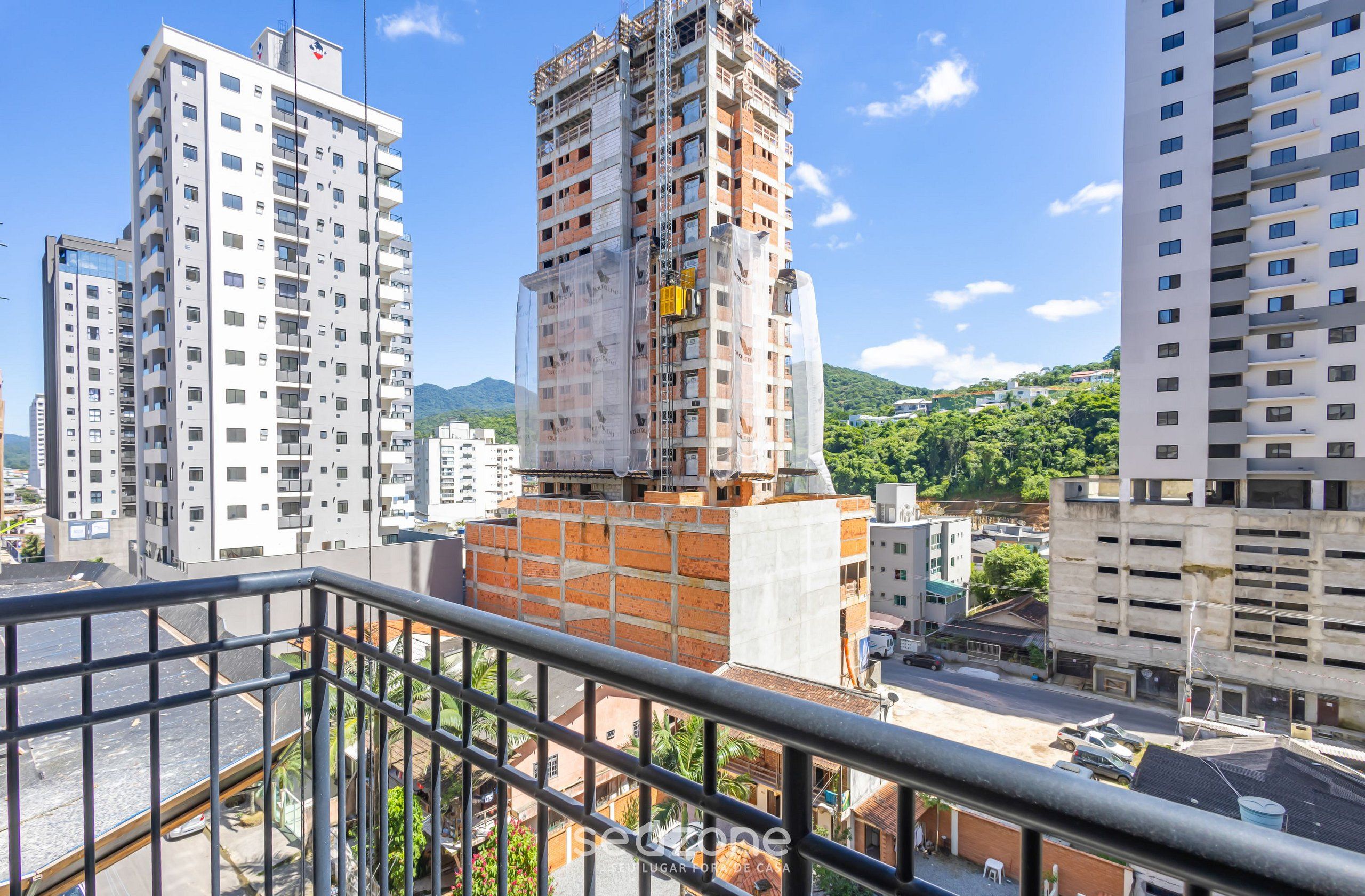 Um edifício alto com vários andares, rodeado por outros edifícios e vegetação.