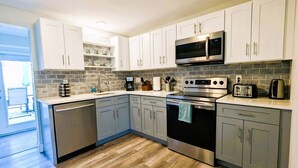 A modern kitchen with white cabinets, a stainless steel microwave, a built-in oven, and a dishwasher.