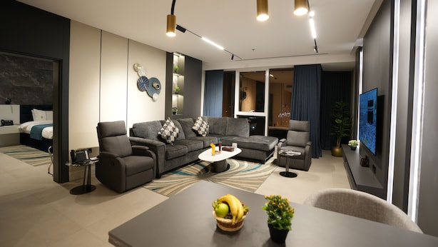 Ein modernes Wohnzimmer mit einer Eckcouch, einem Couchtisch mit Früchten und einem Flachbildfernseher.