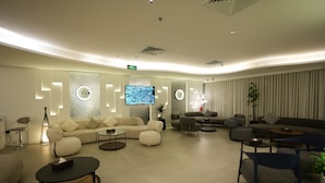 Eine moderne Hotelhalle mit einer Couch, Sesseln, einem Fernseher und einer Pflanze.