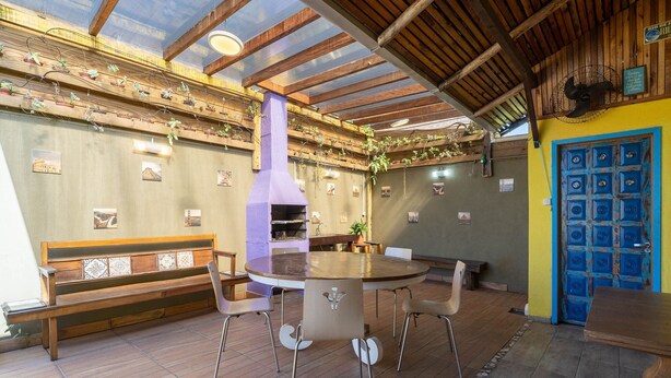 Un comedor con una mesa redonda y sillas, un banco, techo de madera y una puerta azul.