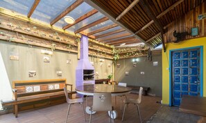 A dining area with a round table and chairs, a bench, a wooden ceiling, and a blue door. - 5BR House w/ Pool Near Beto Carrero SC Jrs0045 (Penha)