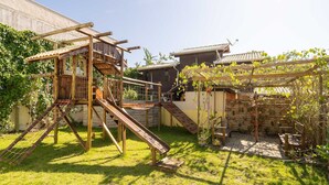 Una estructura de juego de madera con toboganes y elementos para escalar en un patio trasero.