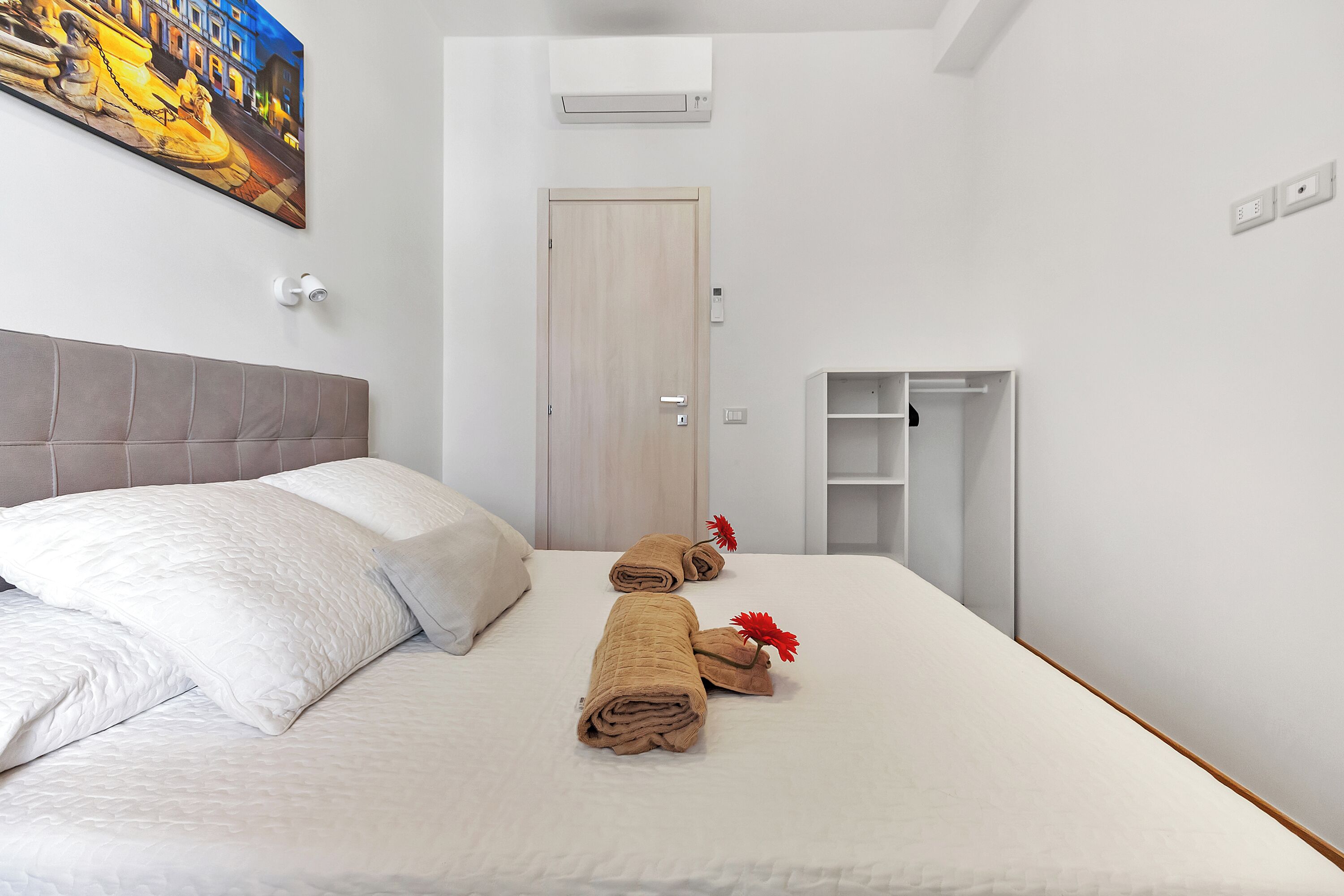 Une chambre d’hôtel avec un lit, une porte, un tableau et une petite armoire.