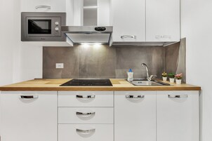 Una cucina moderna con forno a microonde integrato, cappa aspirante in acciaio inossidabile, lavello e piano di lavoro in legno.