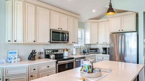 A modern kitchen with white cabinetry, stainless steel appliances, and a marble countertop. - Gold Coast 3BR Condo / Decks, Parking, Walk to Beach (Ocean City)
