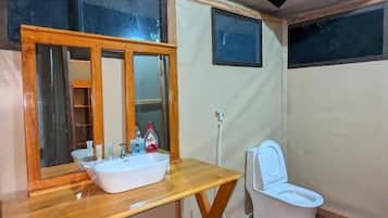 A compact bathroom with a wooden vanity, a white sink, and a toilet.