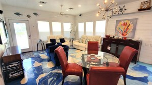 Un salon spacieux avec une table basse en verre, des fauteuils rouges et un canapé beige.