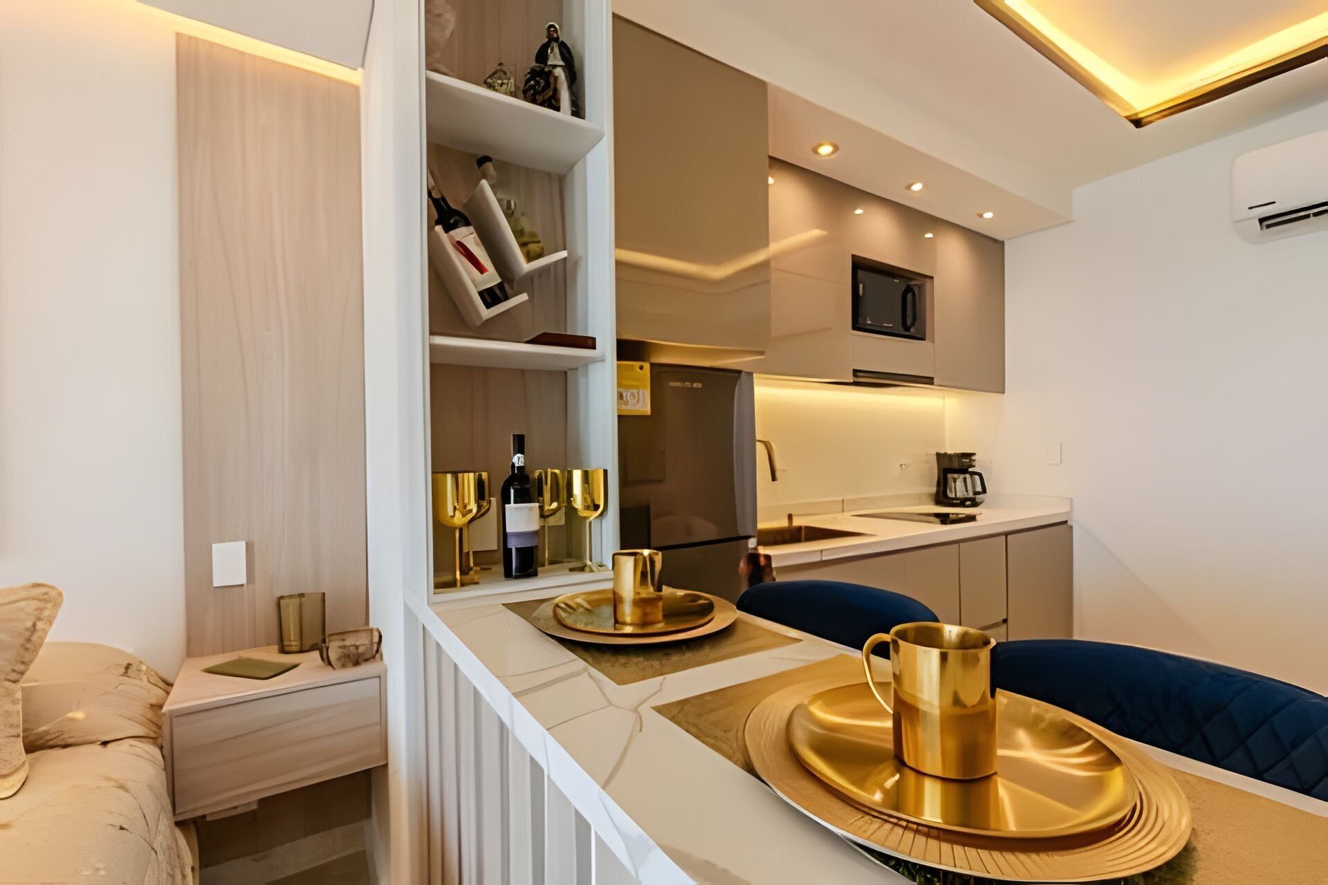 Une cuisine compacte dotée d’appareils modernes, un coin repas avec une chaise bleue et un mini-bar avec des bouteilles de vin.