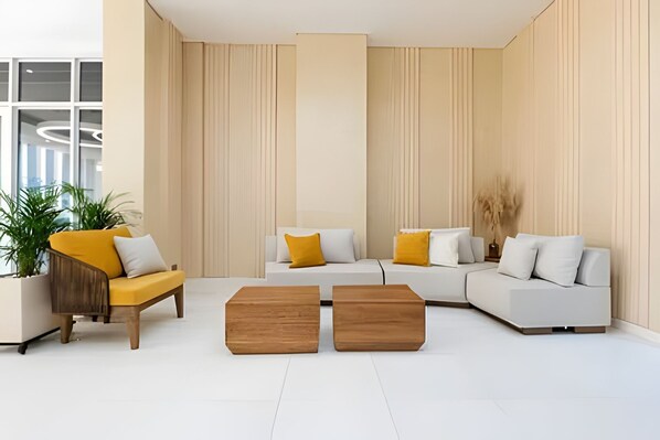 Una sala moderna con un conjunto de sofá, dos mesas de centro de madera y una planta en maceta.
