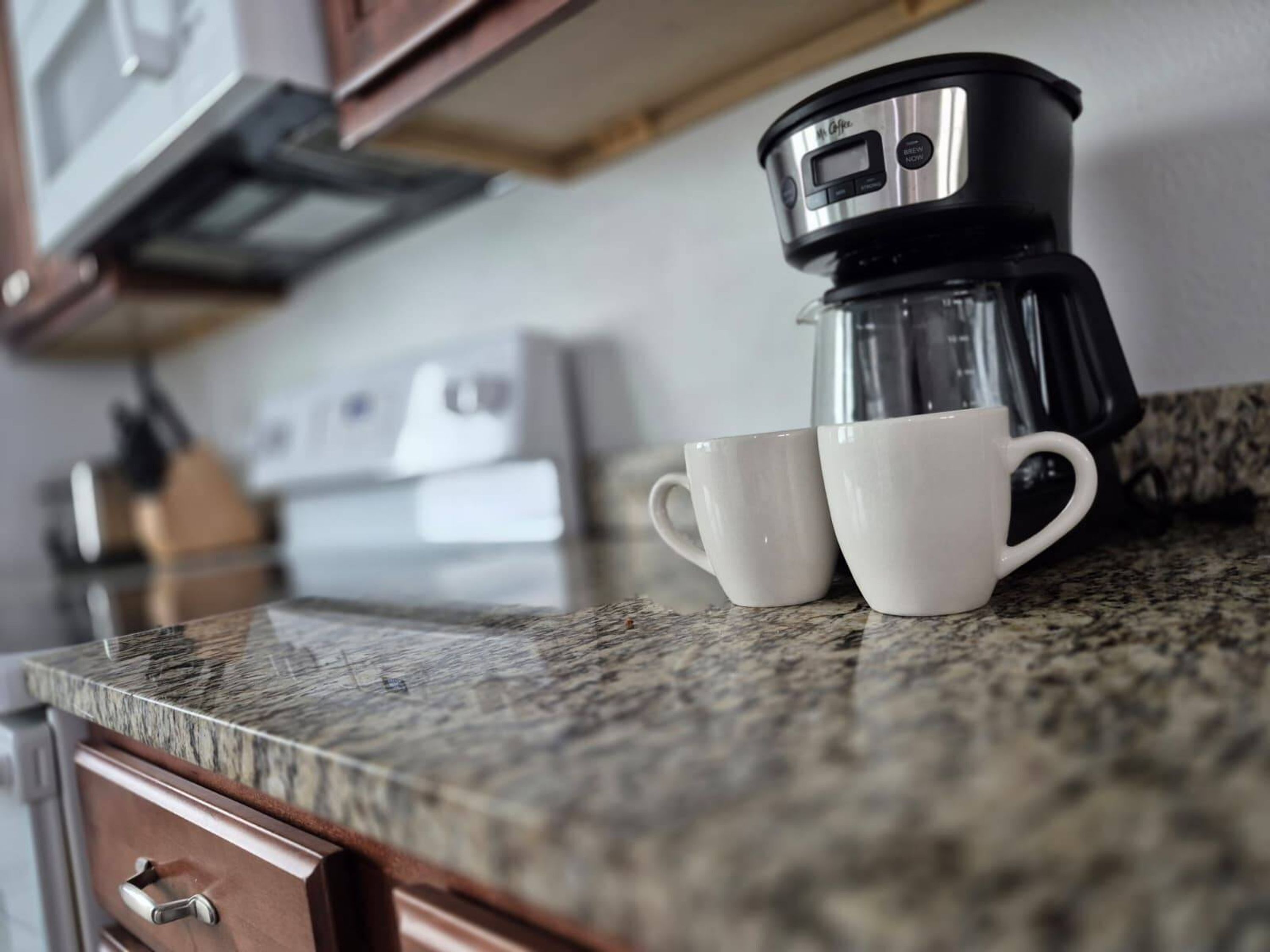 Un piano di lavoro in cucina con una macchina per il caffè e due tazze bianche.