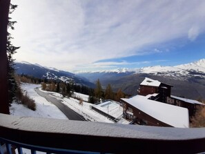 A snow-covered mountain landscape with a road, buildings, and a clear sky.