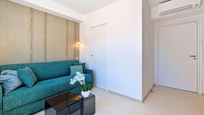 Una sala de estar moderna con un sofá color turquesa, una mesa de centro negra y una puerta blanca.