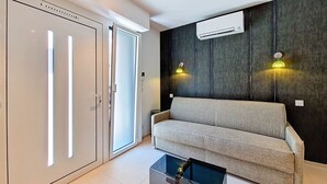 A modern living room with a sofa, a coffee table, and an air conditioning unit on the wall.
