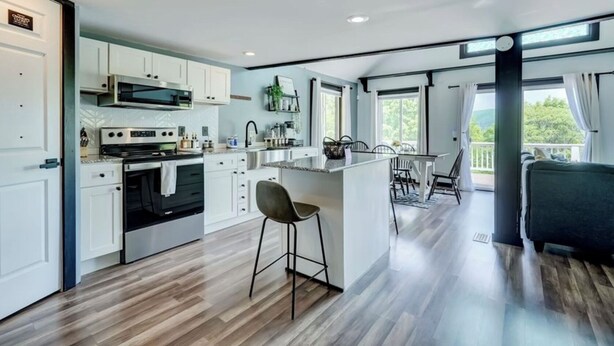 A modern kitchen with white cabinets, a central island, and a dining area with a view.