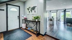 A modern interior with a wooden floor, a console table with plants, a world map on the wall, and a view to a balcony.