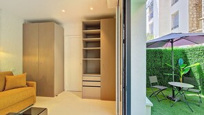 A modern living room with a sofa, a glass coffee table, and a built-in wardrobe. - N&J - JARDIN CORAIL - Garden • AC • Walk to beach (Niza)