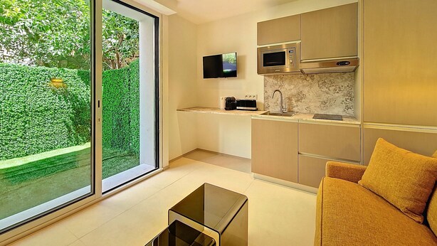 A modern kitchen with a built-in microwave, a sink, and a television mounted above it. - N&J - JARDIN CORAIL - Garden • AC • Walk to beach (Niza)