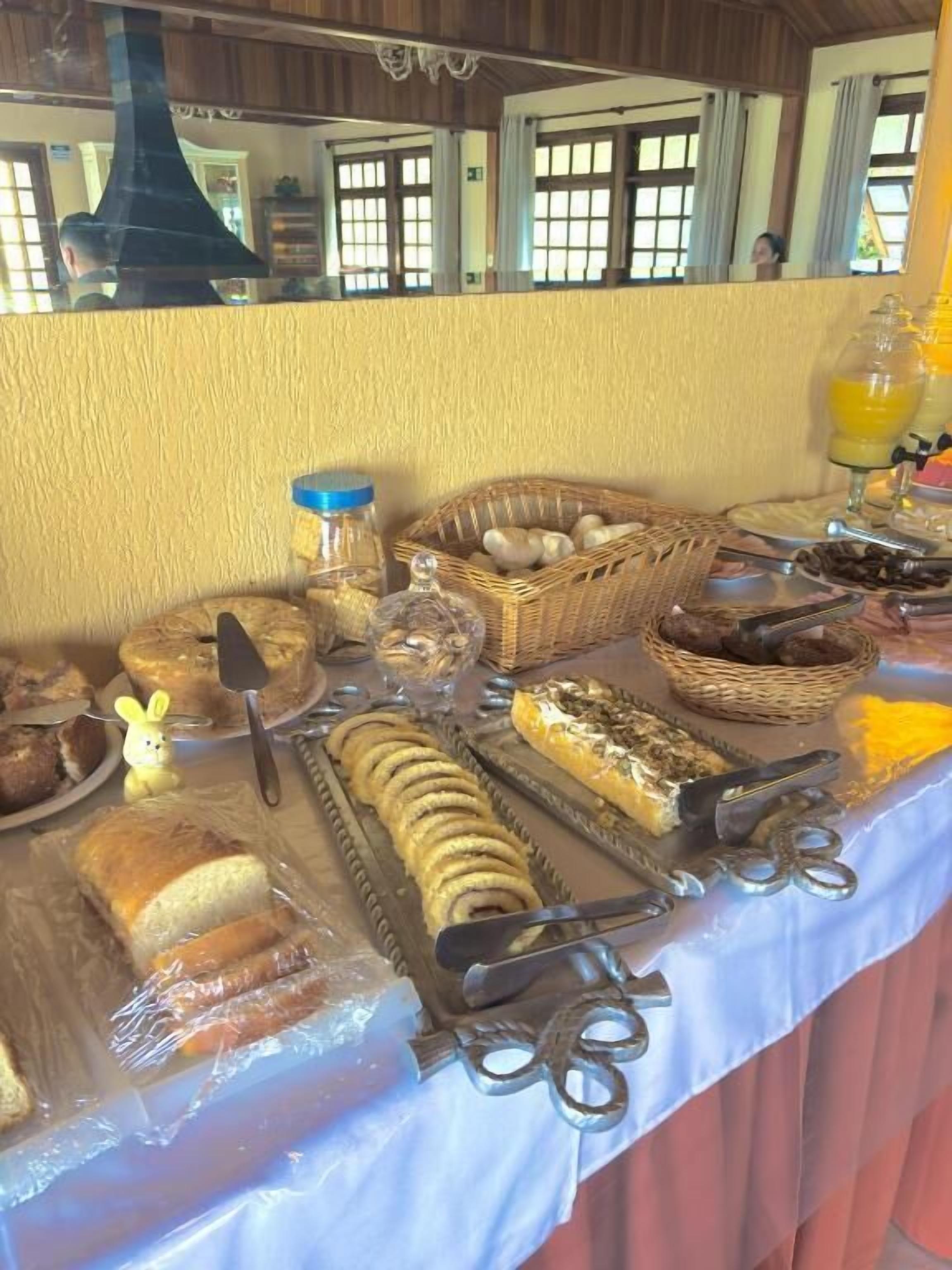 A buffet table with various food items, including bread, pastries, and a fruit punch.
