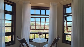 Habitación de esquina con una mesa redonda, dos sillas y vistas a un paisaje a través de amplios ventanales.