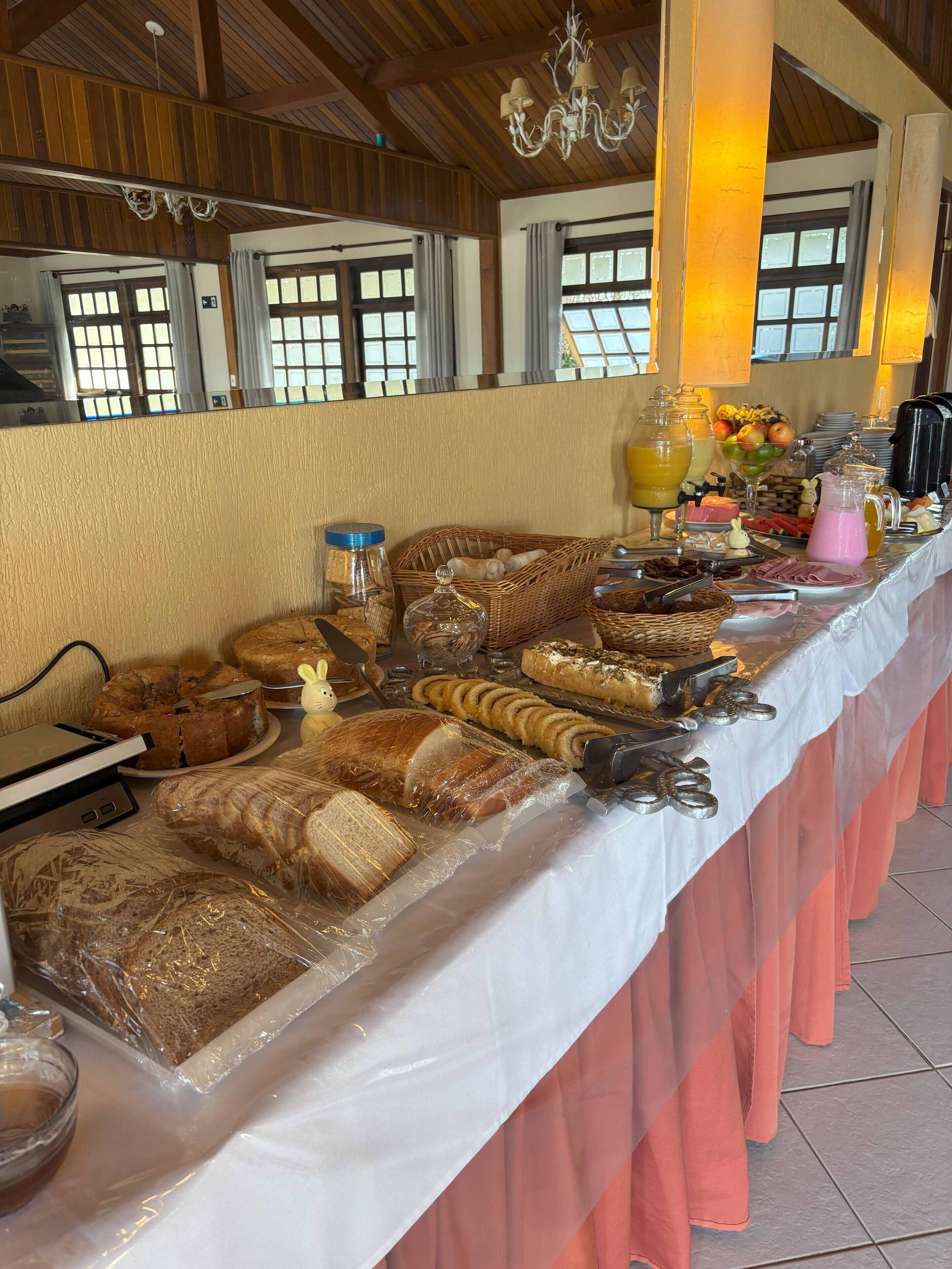 Une table de buffet proposant divers aliments, notamment du pain, des pâtisseries et un saladier de fruits.