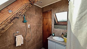 Ein Badezimmer mit Holzboden, einer Dusche, einem Waschbecken und einem Spiegel.