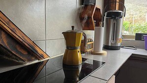 Eine Küche mit Kaffeemaschine, Wasserkocher und Thermoskanne auf der Arbeitsfläche.