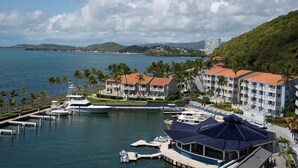 Un port de plaisance où sont amarrés des yachts, un espace piscine et un bâtiment d’hôtel avec de nombreux balcons donnant sur l’eau.