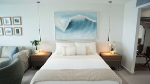 Une chambre avec un grand lit, des tables de chevet avec des lampes, un tableau accroché au mur et une vue sur la pièce.