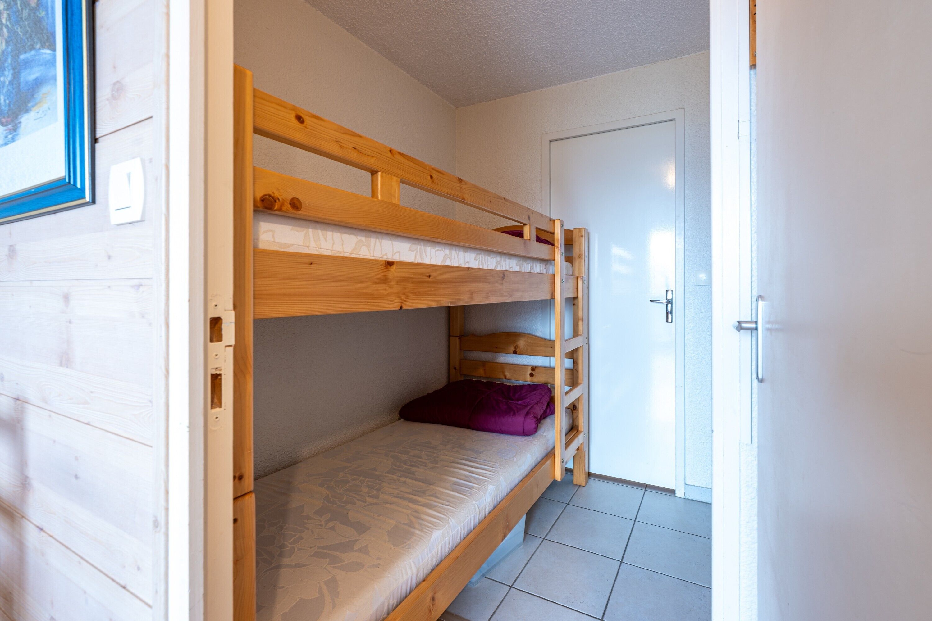 Habitación con literas, una puerta y un cuadro en la pared.