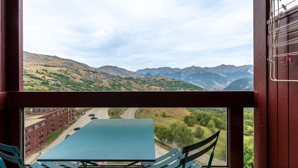 A table and chairs inside a room with a view of a mountainous landscape through a window. - Studio Apartment 'Avec Vue Splendide' with Mountain View and Balcony (Villarembert)