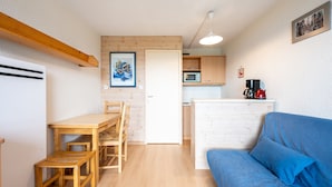 A compact living space with a kitchenette, a dining area, and a sofa. - Studio Apartment 'Avec Vue Splendide' with Mountain View and Balcony (Villarembert)