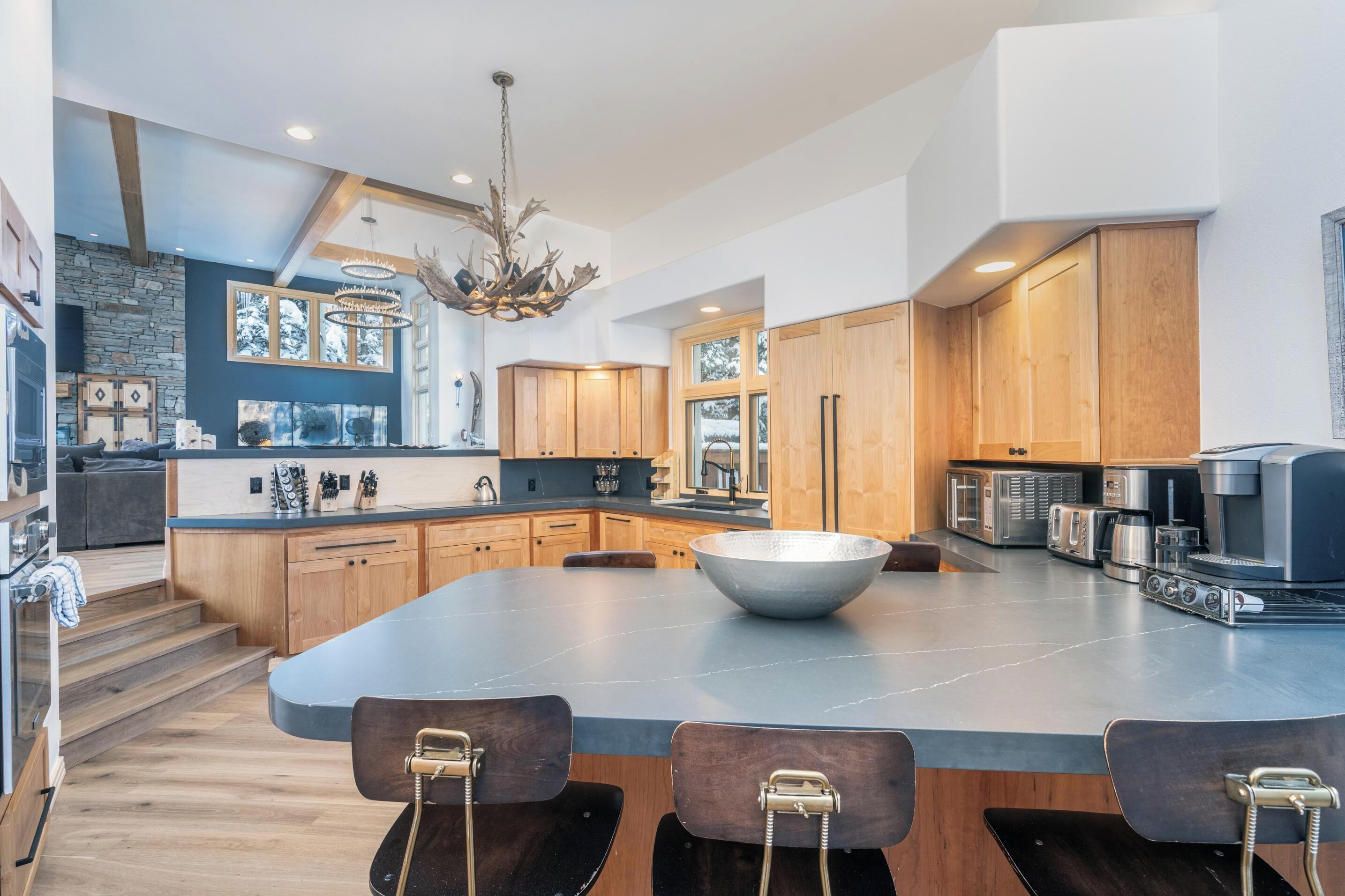 A modern kitchen with a large island, wooden cabinets, and a stone accent wall.