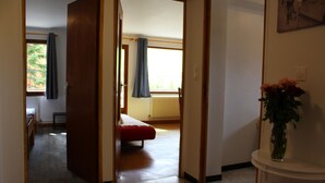 A hotel room with a bed, a window with curtains, a radiator, and a small table with a vase of flowers. - Family apartment for 6 people in a quiet residence in Sainte Marie (Vars)