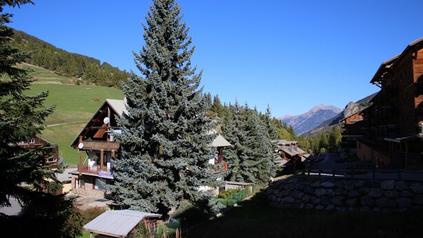 A mountain lodge with a wooden exterior, a balcony, and a view of the surrounding mountains. - Family apartment for 6 people in a quiet residence in Sainte Marie (Vars)