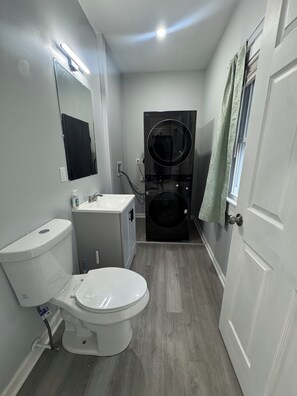 A compact bathroom with a toilet, sink, and a black washing machine. - Spacious 4-bedroom apartment in brilliant Bristol with AC (Bristol)